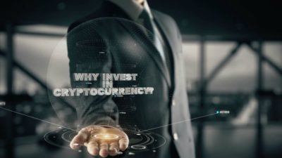 Businessman with his palm open containing a hologram saying 'Why Invest In Cryptocurrency?'