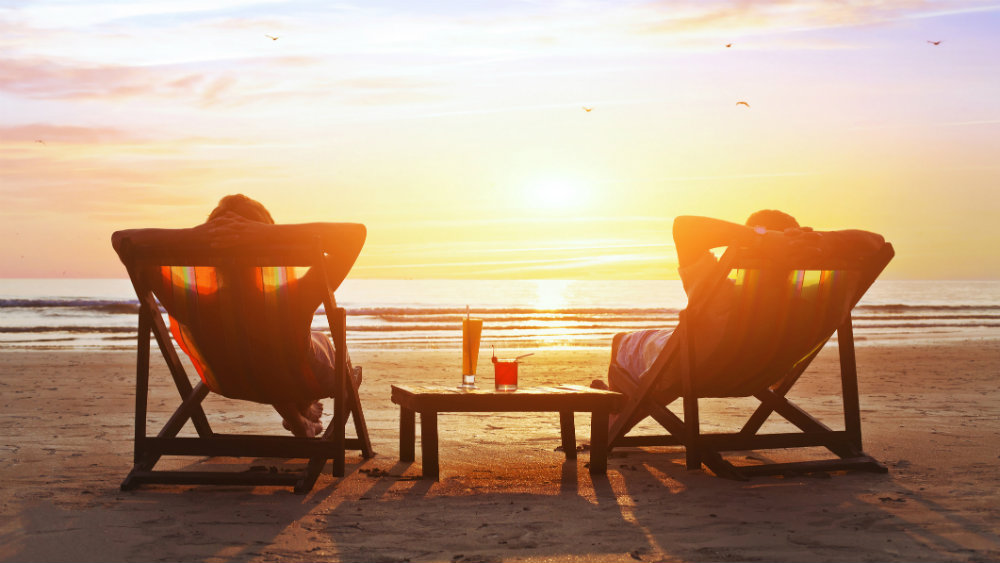 Couple relaxing on a beach in front of a sunset