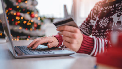 edit Women wearing red sweater shopping online and using credit card at home office