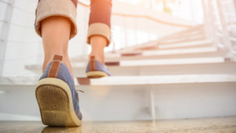 Young adult woman walking up the stairs with sun sport background
