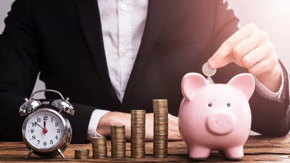 Businessman's hand putting coin in piggy bank