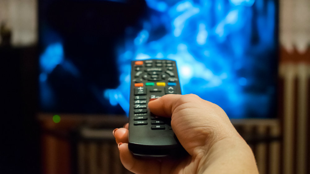 Lady holding remote control pointed towards a TV