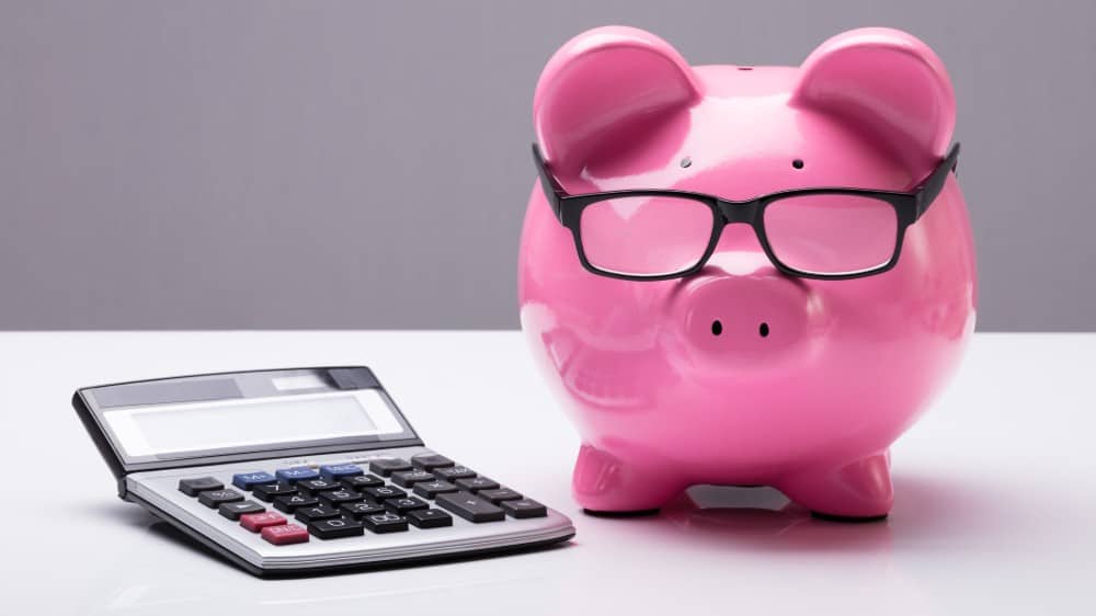 Edit Close-up of a piggy bank with glasses and a calculator on the desk