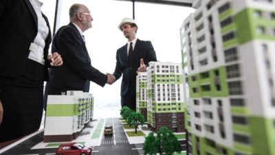 Business people standing near houses models
