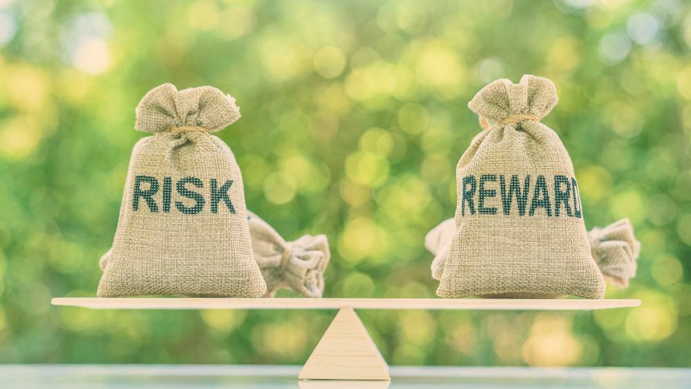 Bag labeled "Risk" and bag labeled "Reward" balanced on a scale