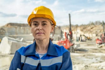 A worker wears a hard hat outside a mining operation.