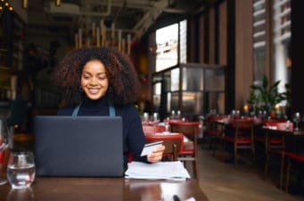 A worker uses a laptop inside a restaurant.