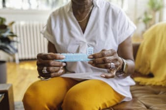 A patient takes medicine out of a daily pill box.