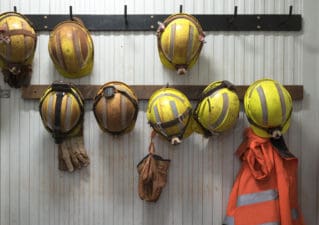 Safety helmets and gloves hang from a rack on a mining site.