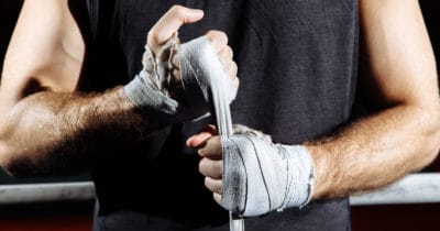 a person prepares to fight by taping their knuckles