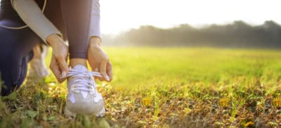 runner ties shoe while stopped on grass outside