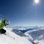 Skiier goes down the mountain on a sunny day