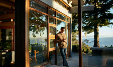 person on phone leaning against outside wall with scenic view at airbnb rental property