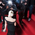 A celebrity is photographed on a red carpet.