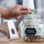 customer adds cash to tip jar at business