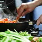 chef cooks healthy vegetables on hot stove with steam