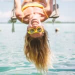 upside down girl playing on swing over the sea,