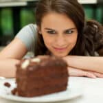 woman stares at chocolate layer cake