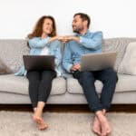 Couple working on laptops at home and fist bumping