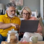 middle-aged couple work together on laptop
