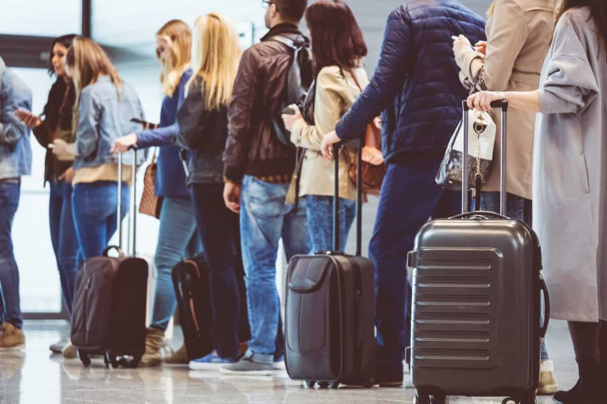 people stand in a line to wait at an airport