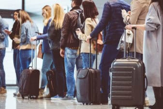 people stand in a line to wait at an airport