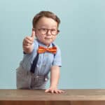 boy in bowtie and glasses gives positive thumbs up
