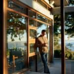 person on phone leaning against outside wall with scenic view at airbnb rental property