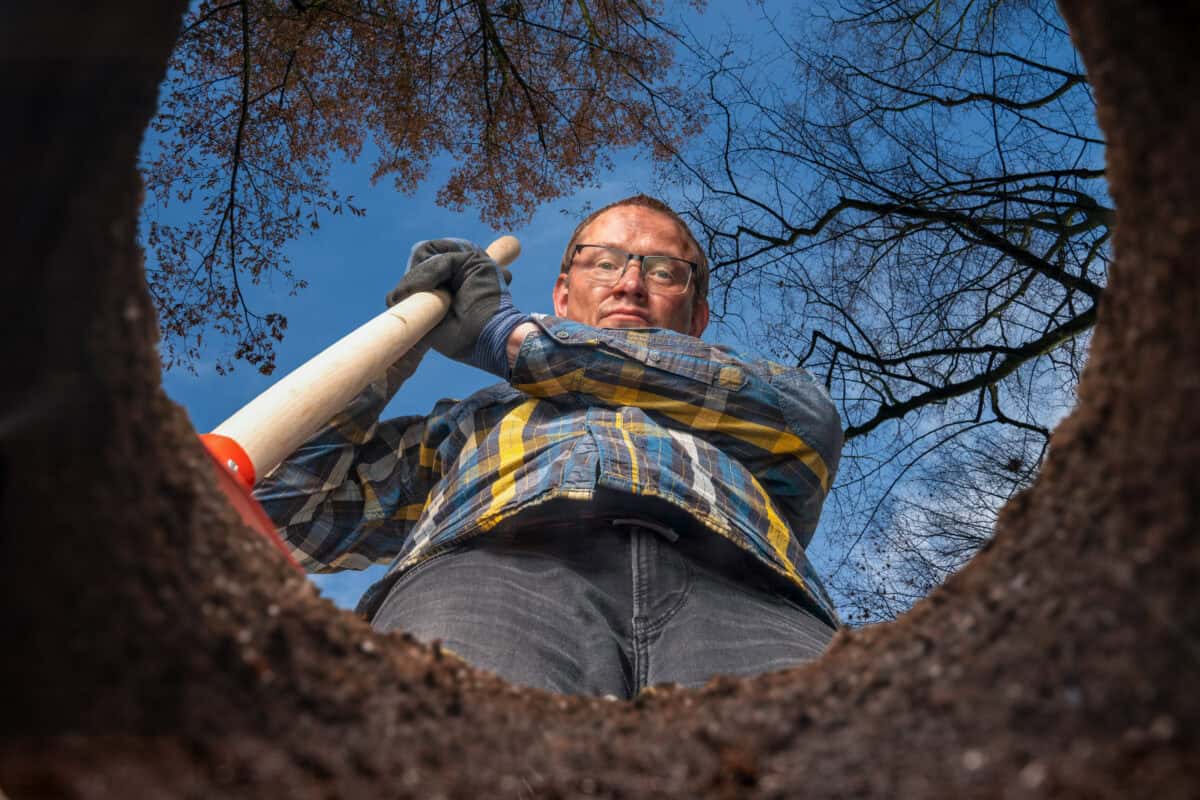 man with shovel stands by a hole
