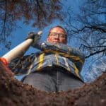 man with shovel stands by a hole