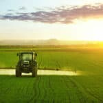 Tractor spraying a field of wheat with fertilizer