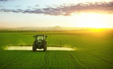 Tractor spraying a field of wheat with fertilizer