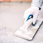 industrial worker on construction site laying sealant for waterproofing cement